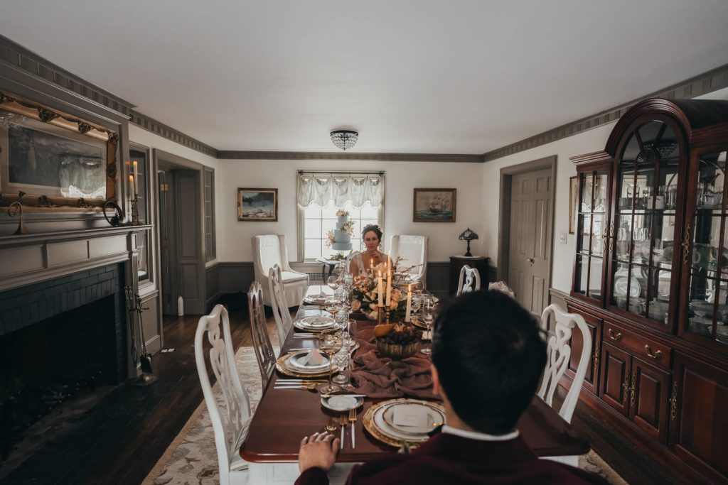 Image of bride looking at groom from far end of a ornately decorated table
