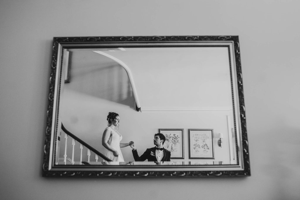 black and white reflection of bride and groom walking down the stairs
