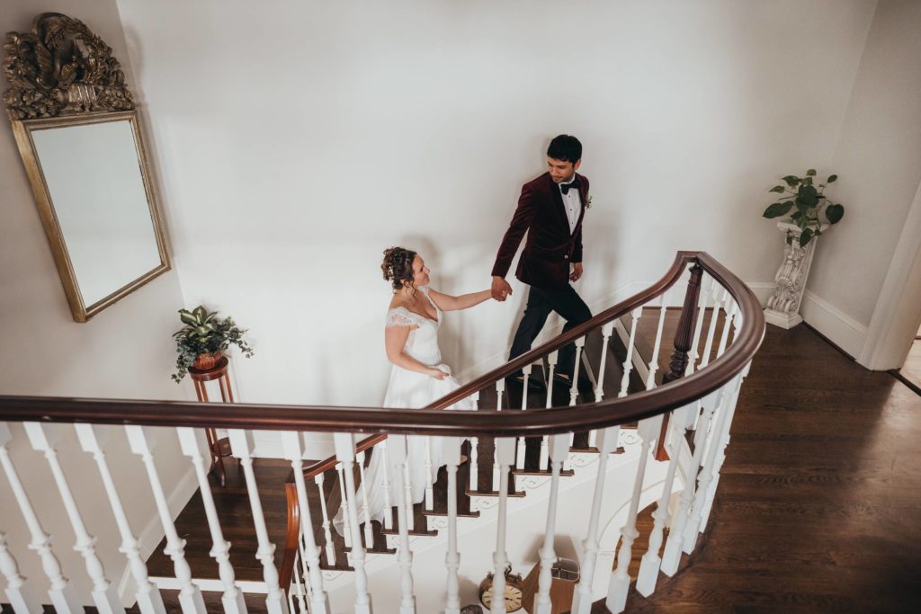 Groom looks back at bride while they walk up the stairs