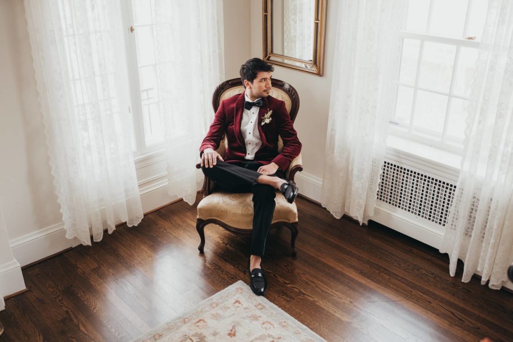 Groom sitting in high backed chair in corner of room